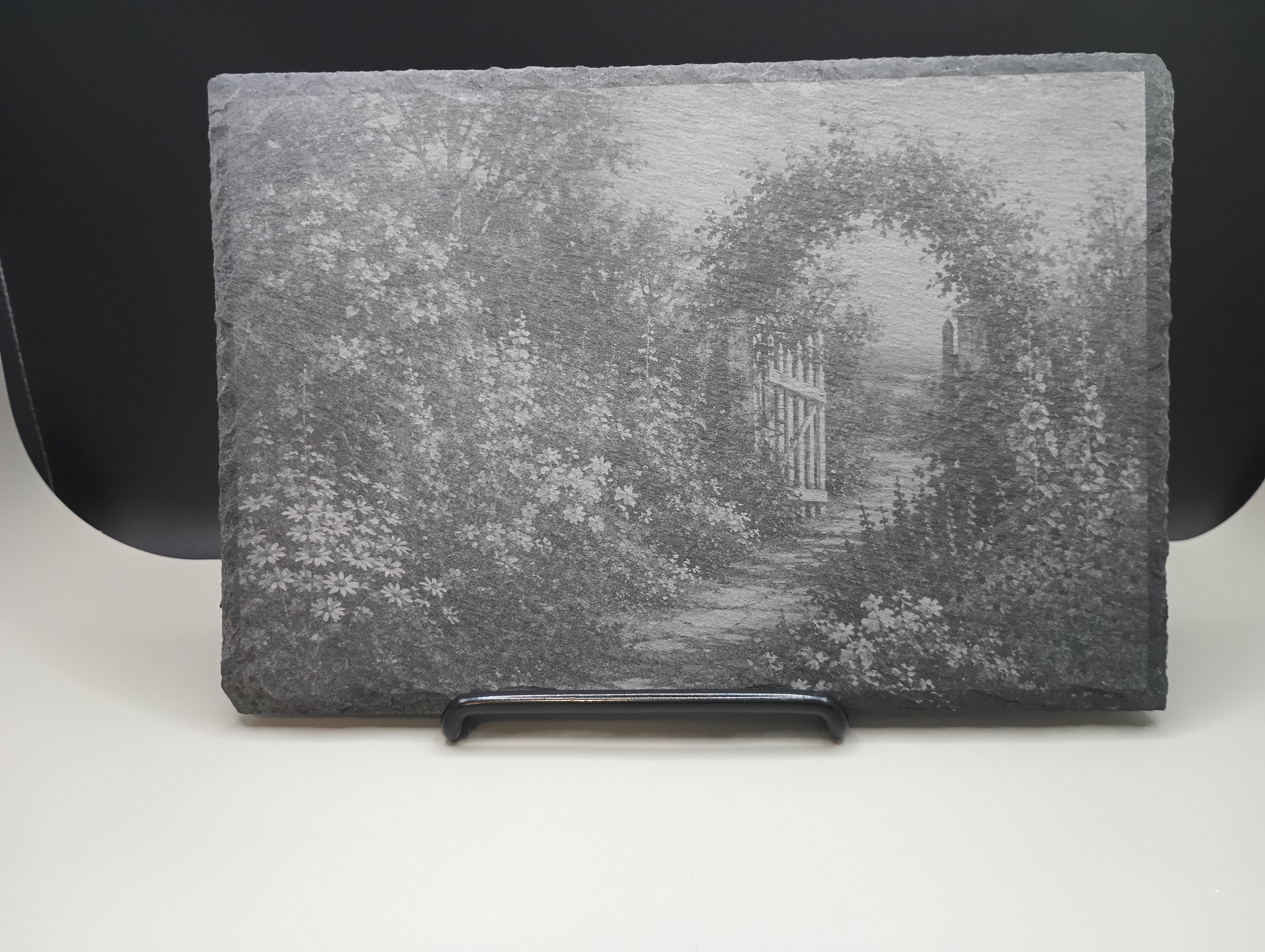 Decorative stone with a garden scene featuring a gate and archway.