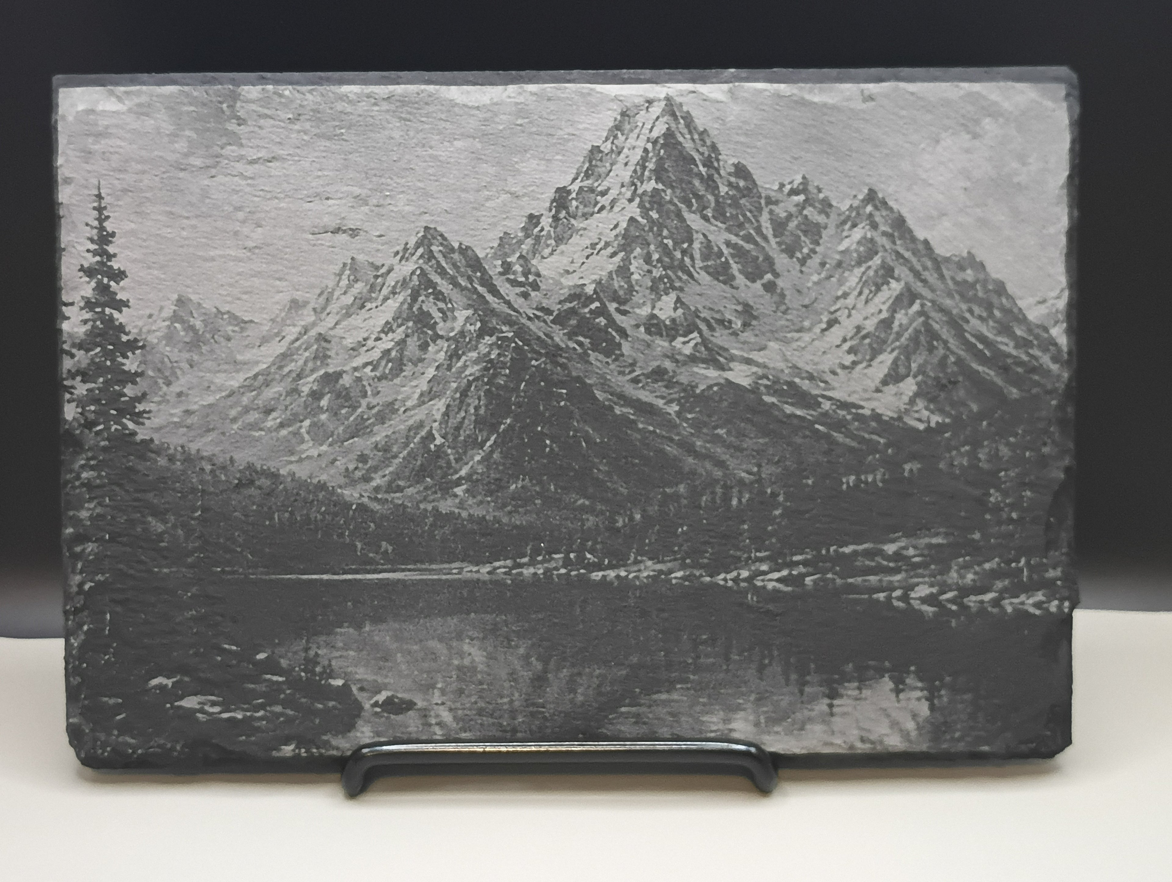 Slate with engraved mountain landscape on a white background