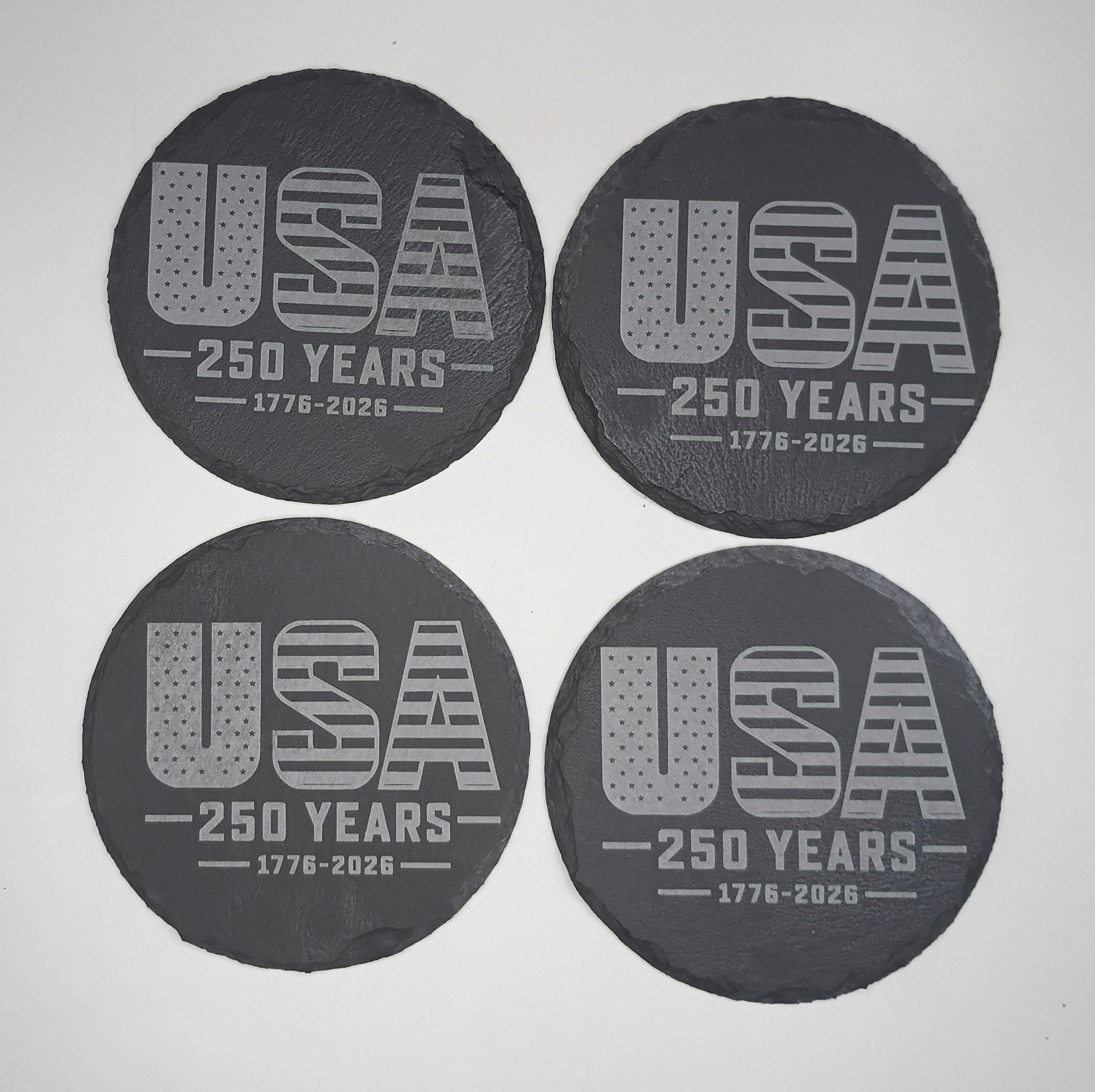 Four black coasters with 'USA 250 Years 1776-2026' text on a white background