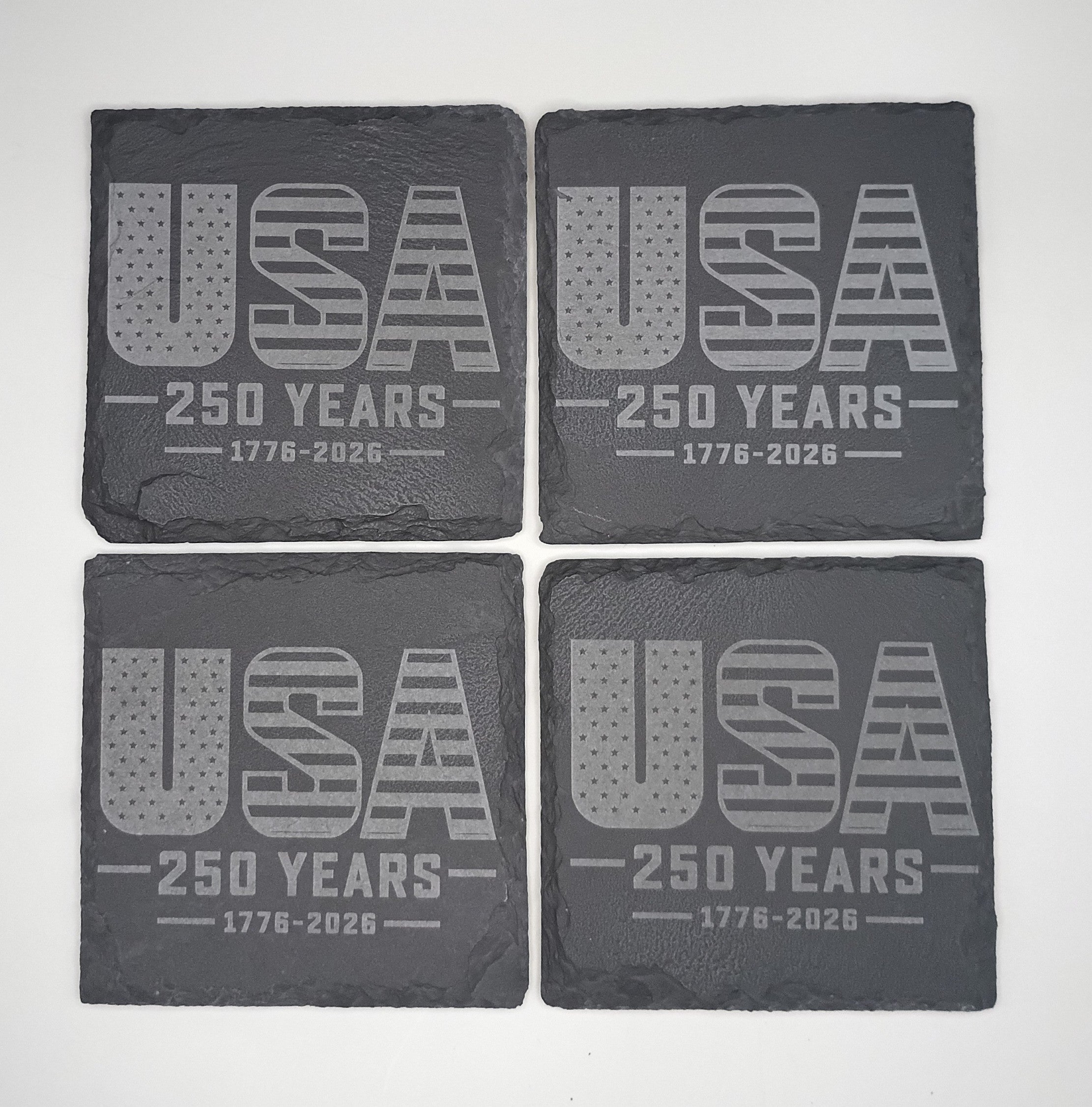 Four dark gray coasters with 'USA 250 Years 1776-2026' text on a white background